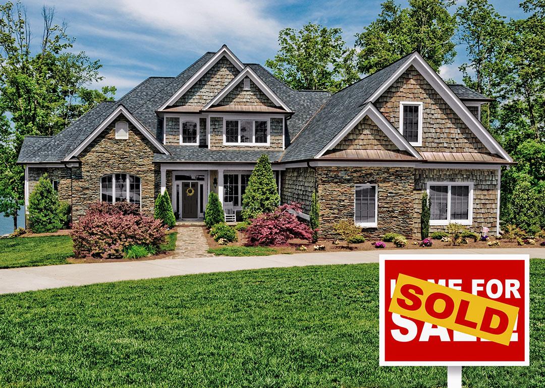 Home with green lawn and "For sale" sign covered by the word "sold."