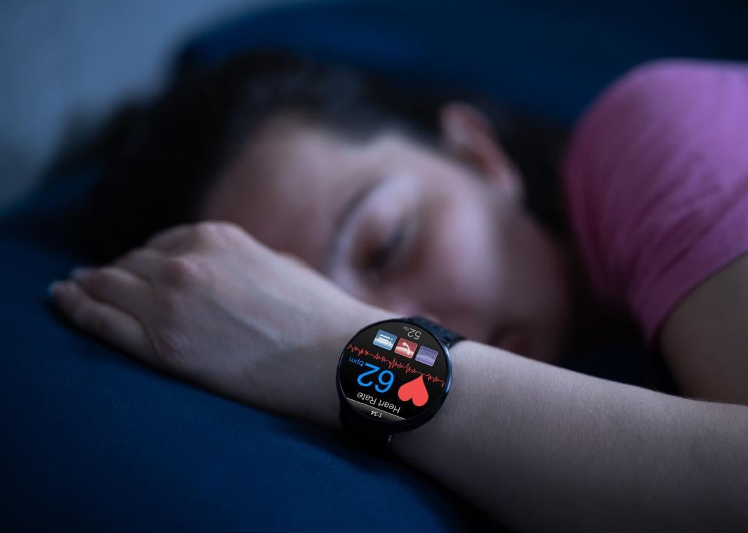 Person wearing sleep tracking heart rate monitor smartwatch in bed.