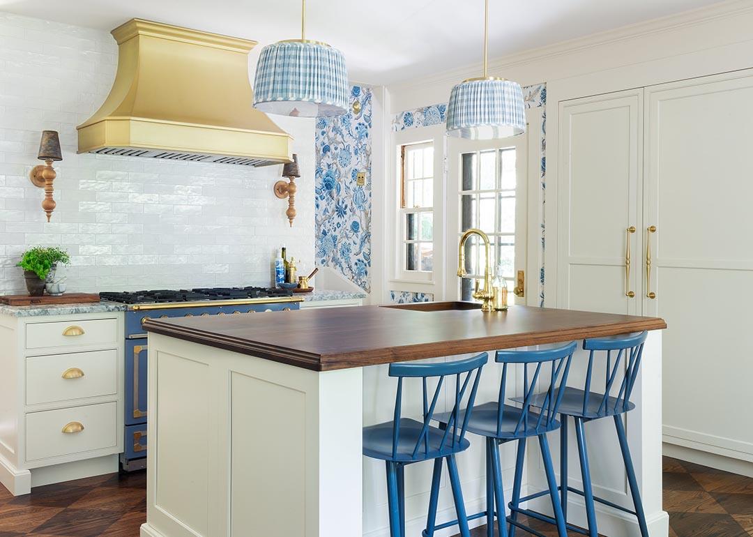 French style country kitchen with white tile, dark countertops and blue and white wallpaper accents.