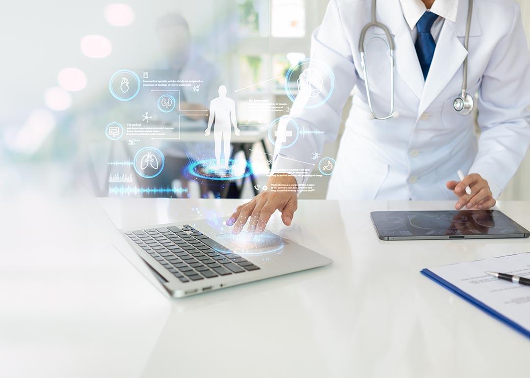 Doctor using laptop with elements of futuristic icons superimposed, symbolizing AI and technology.
