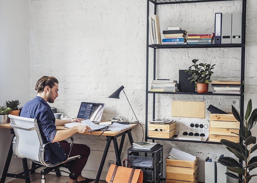 View of back of person sitting at a desk in white office chair in modern office with white walls.