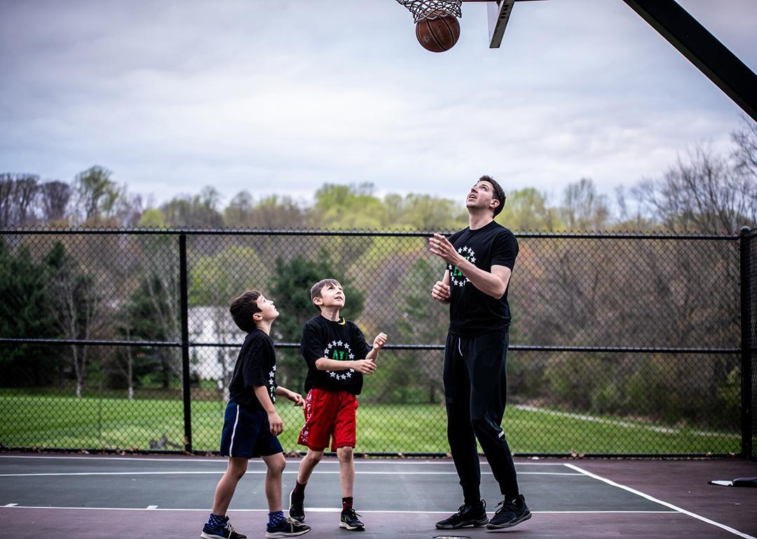 A private sports coach in a basketball session with two young boys.