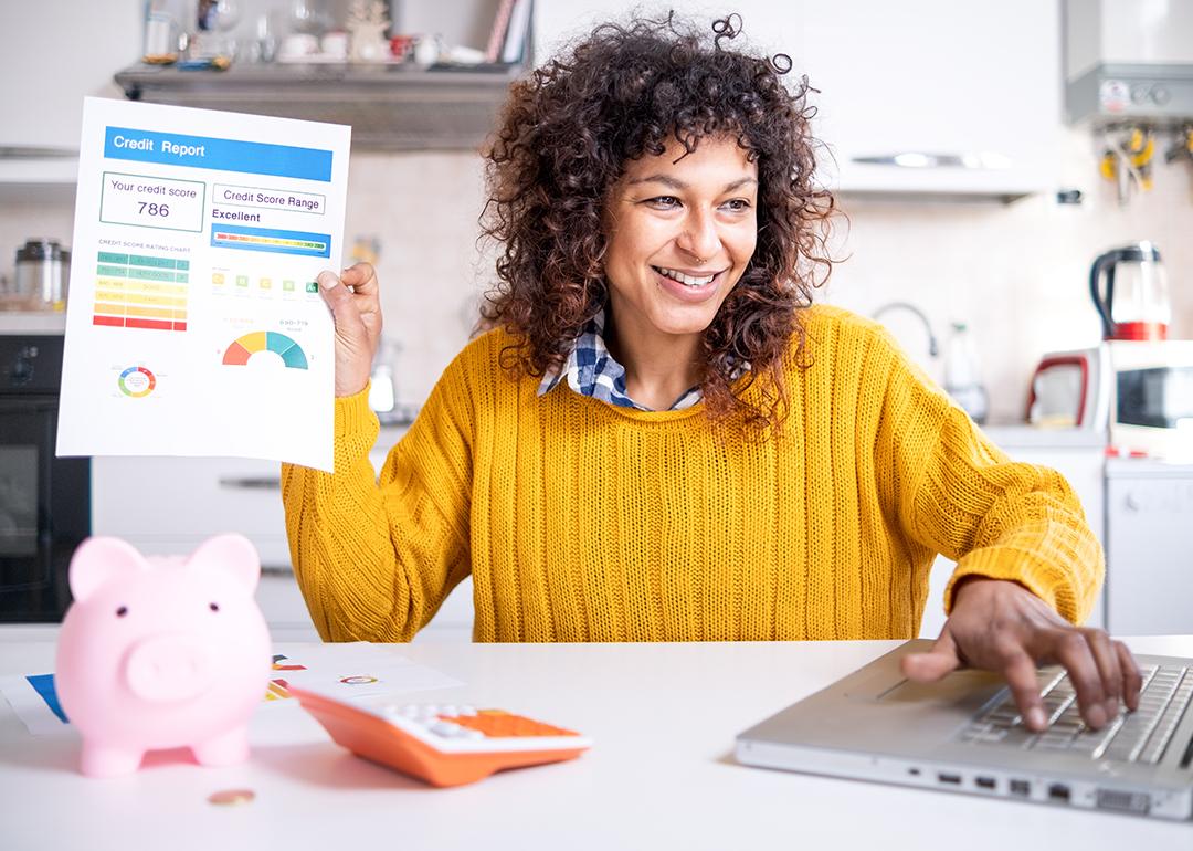 A woman happily holding up a good credit score report.