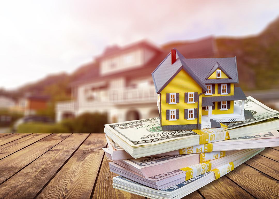 A figure of a house on top of bundles of cash.