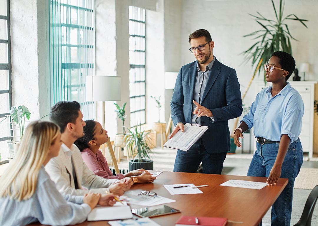 Five members of a diverse business team in a meeting in an office.