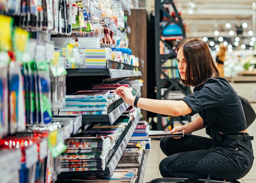 A young woman choosing school supplies at a supermarket.