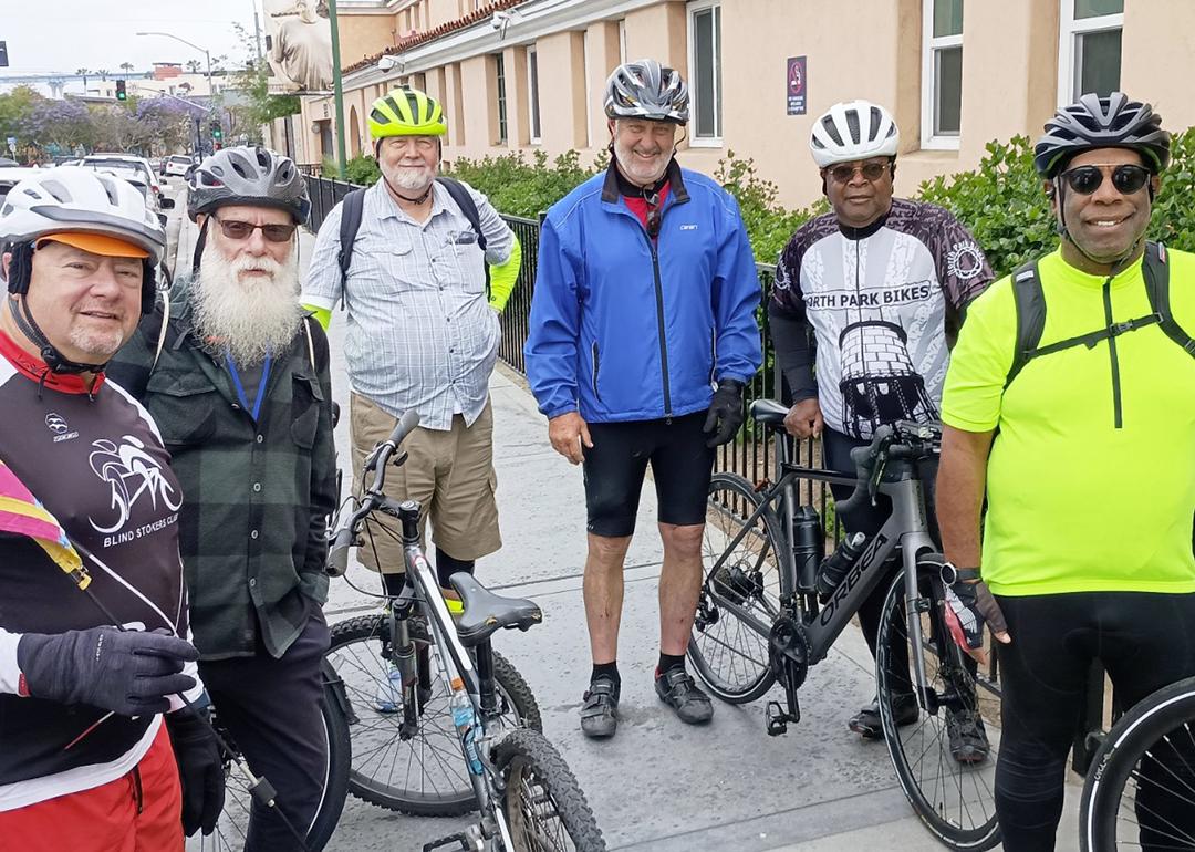 A group of participants in full biking gear posing for a photograph with their bicycles.