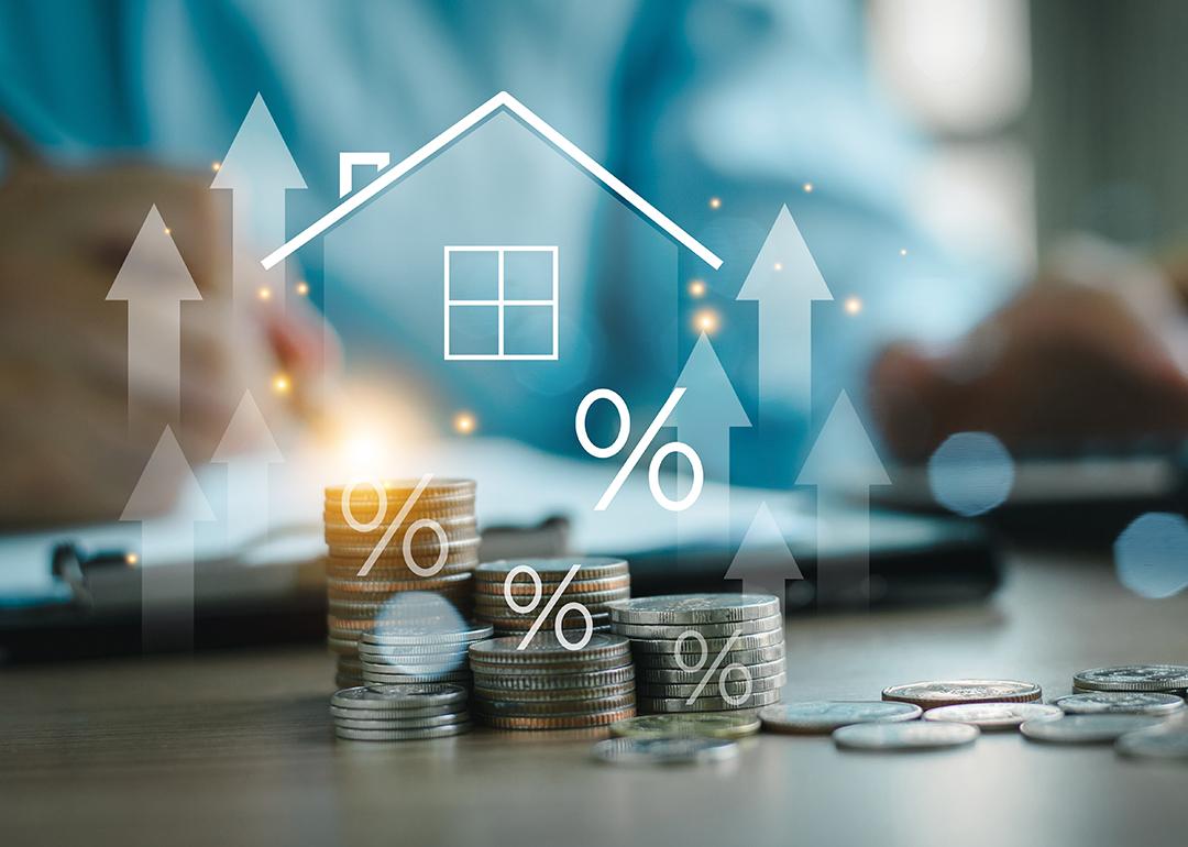 Home insurance and real estate protection concept graphics over stacks of coins.