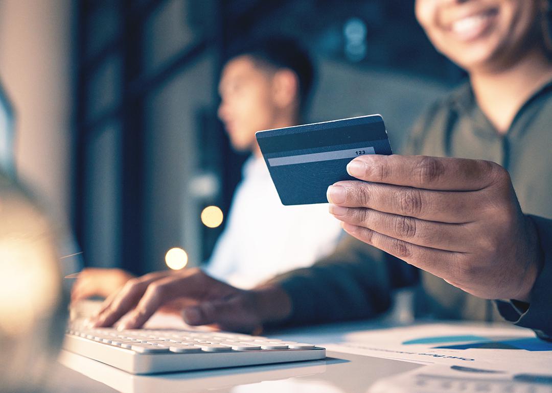 An employee holding a credit card while making an online purchase in the office.