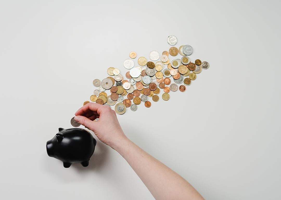 Coins being inserted into a black piggy bank.