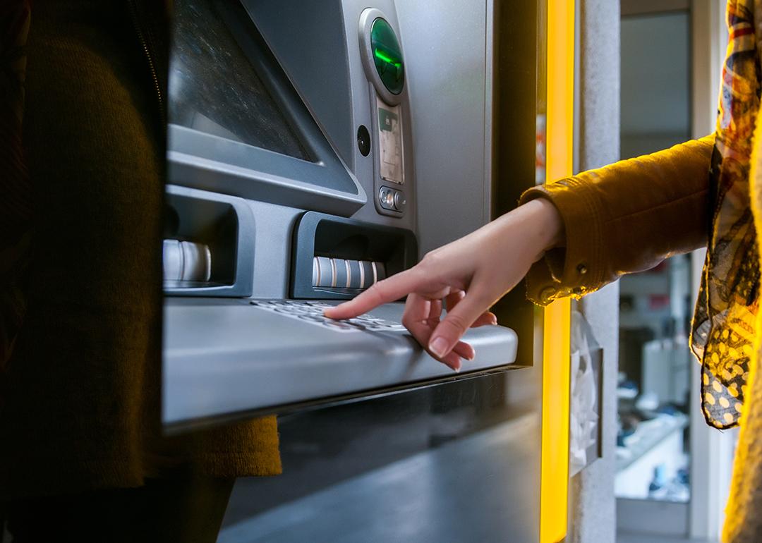 A woman entering info in an ATM to withdraw money.