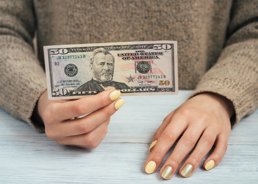 A woman holding a $50 banknote.