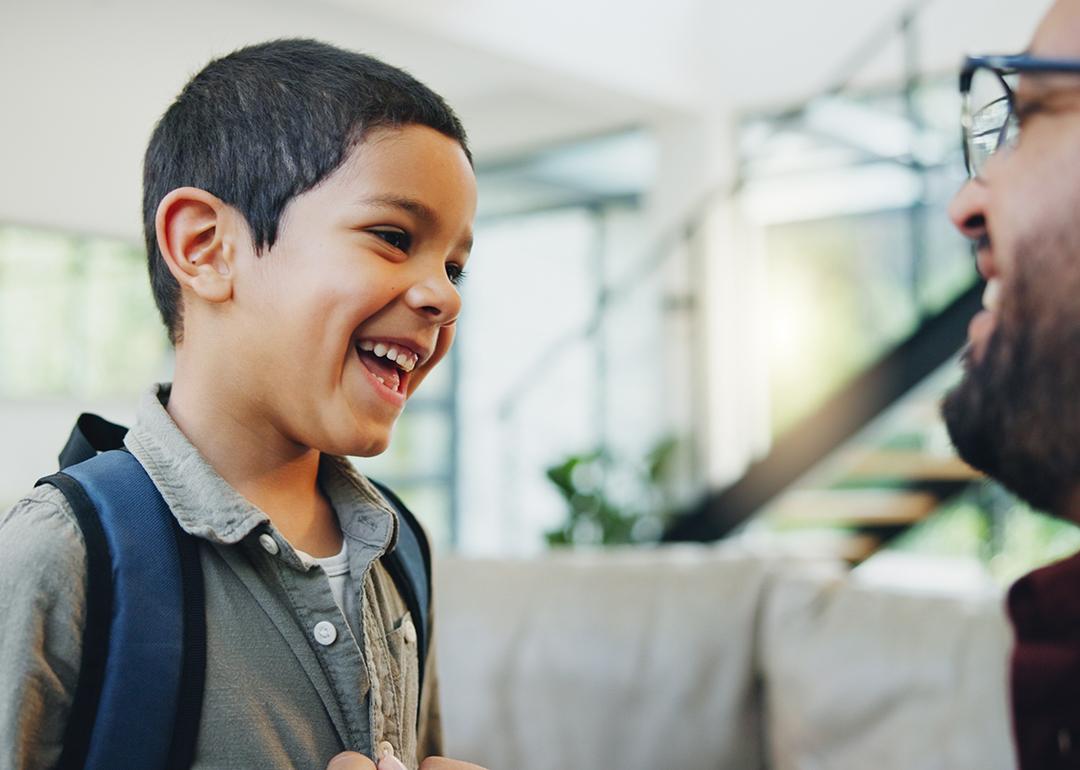 A young boy getting ready to go to school talking with his dad.