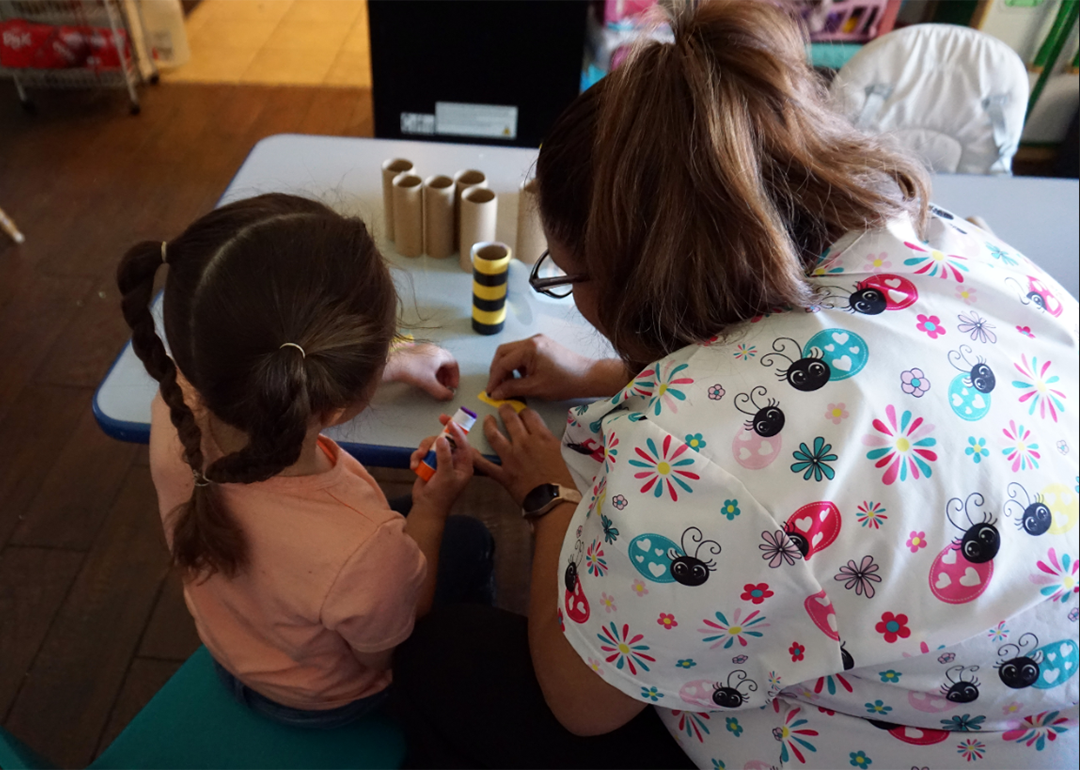 Maggi, a child care provider in New Mexico, with a preschooler in her care working on an art project.