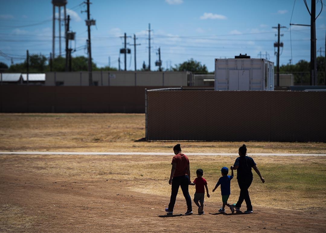 Immigrant woman and children walk across a field as U.S. Immigration and Customs Enforcement (ICE) and Enforcement and Removal Operations (ERO) hosts a media tour at the South Texas Family Residential Center, August 2019.
