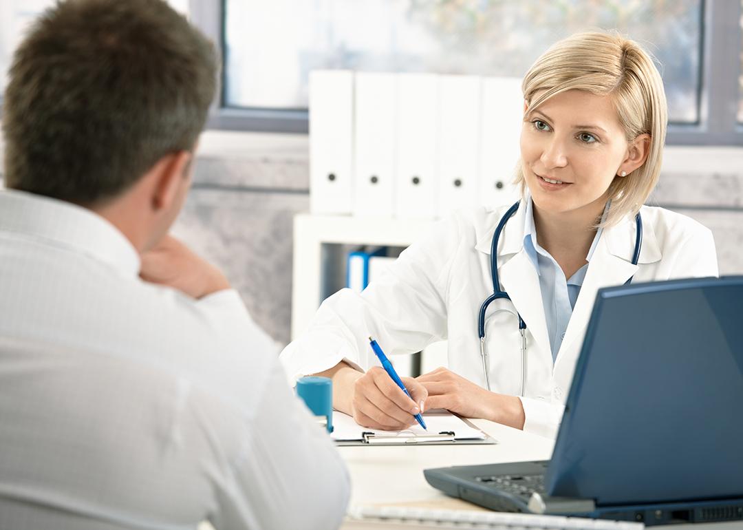 A doctor takes notes while consulting with her patient.