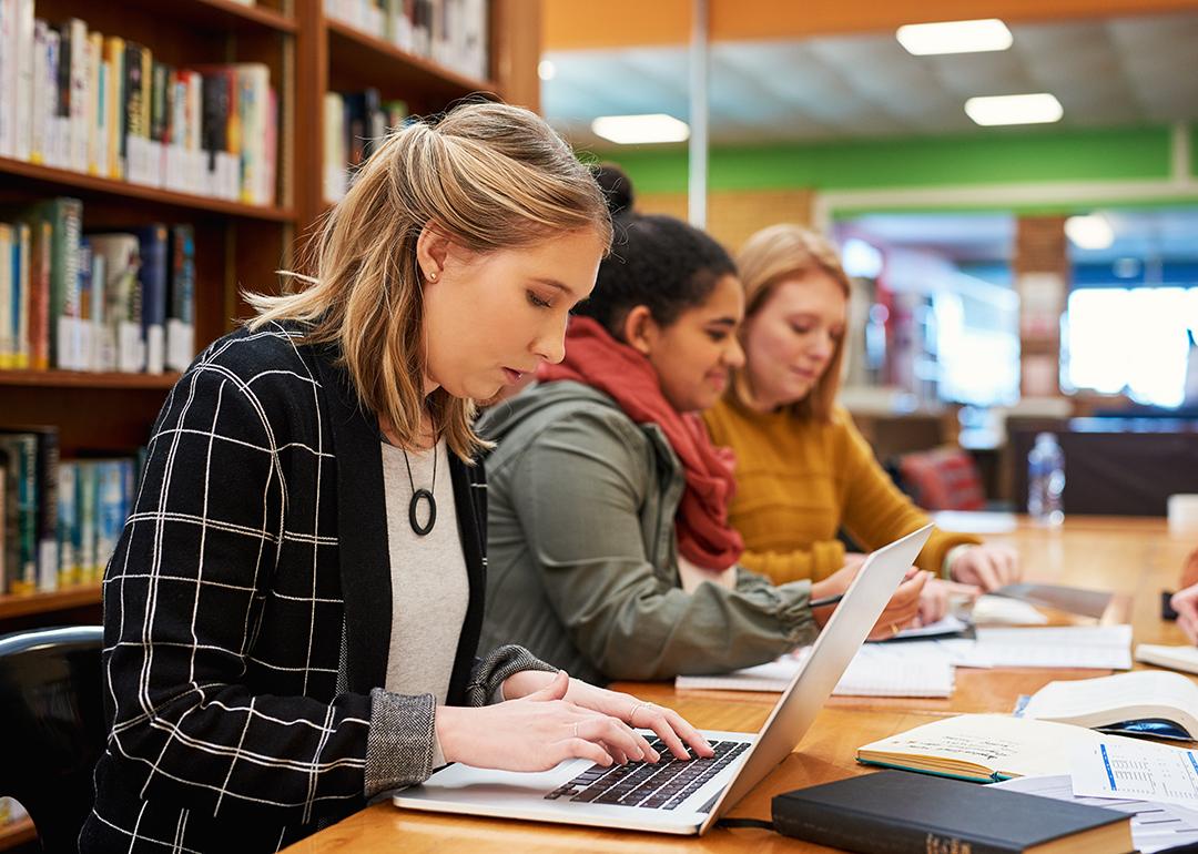 A female marketing professional composes email in her laptop in an office library.