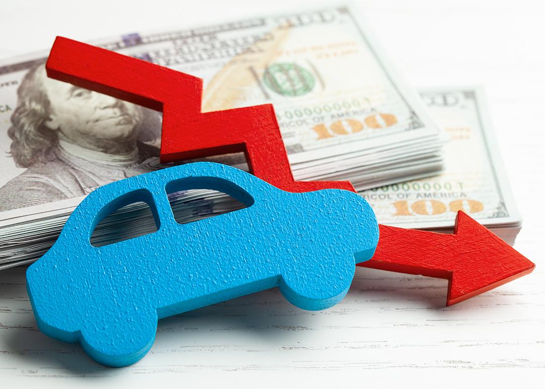 Figure of a car and declining arrow on top of U.S. banknotes.