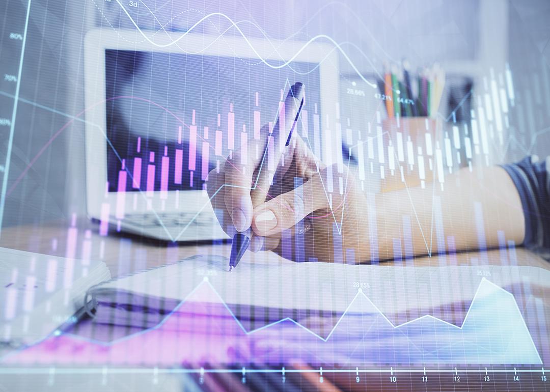 Businesswoman writing notes illustrated with finance, forex charts graphics.