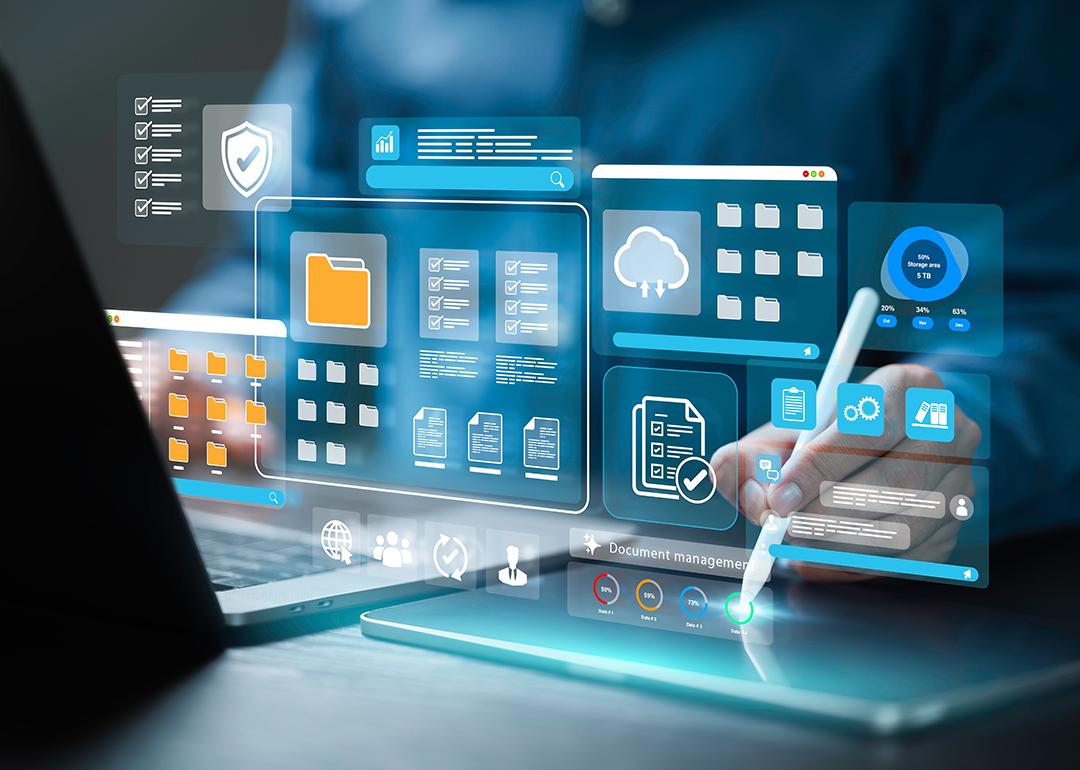 Employee working on a laptop with holographic illustrations of document management software concepts.