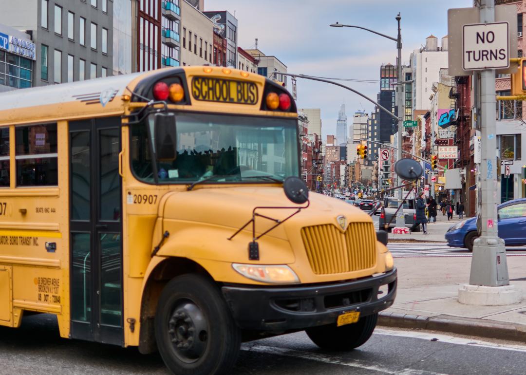 A yellow school bus passing a street in New York City.