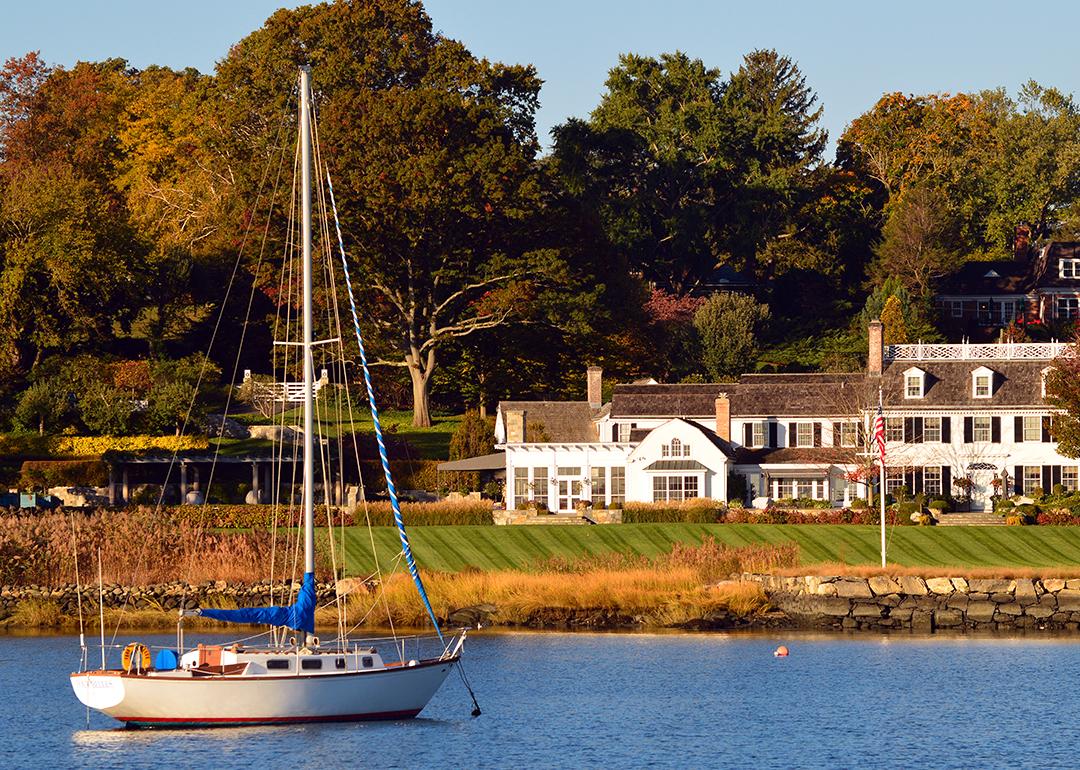 A sailboat moored off-shore near a luxury waterfront home in Greenwich, Connecticut.