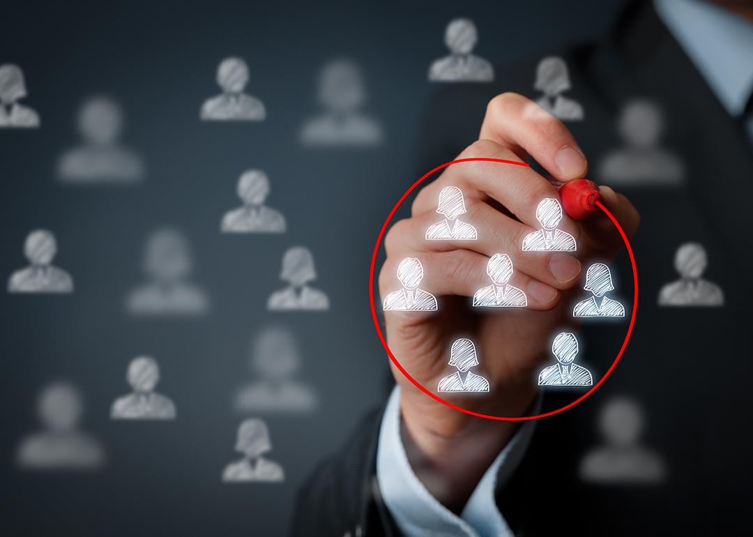 A hand encircling a group of business people graphic figures with a red marker.