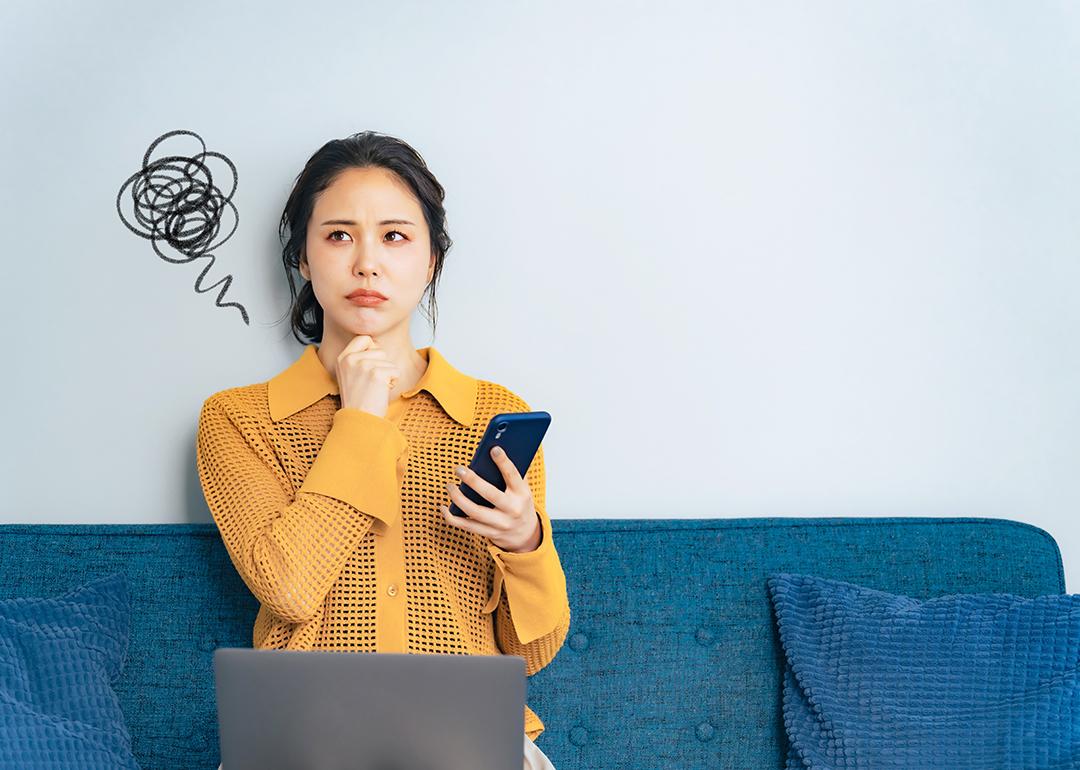 A young woman trying to think of an idea while holding her phone.