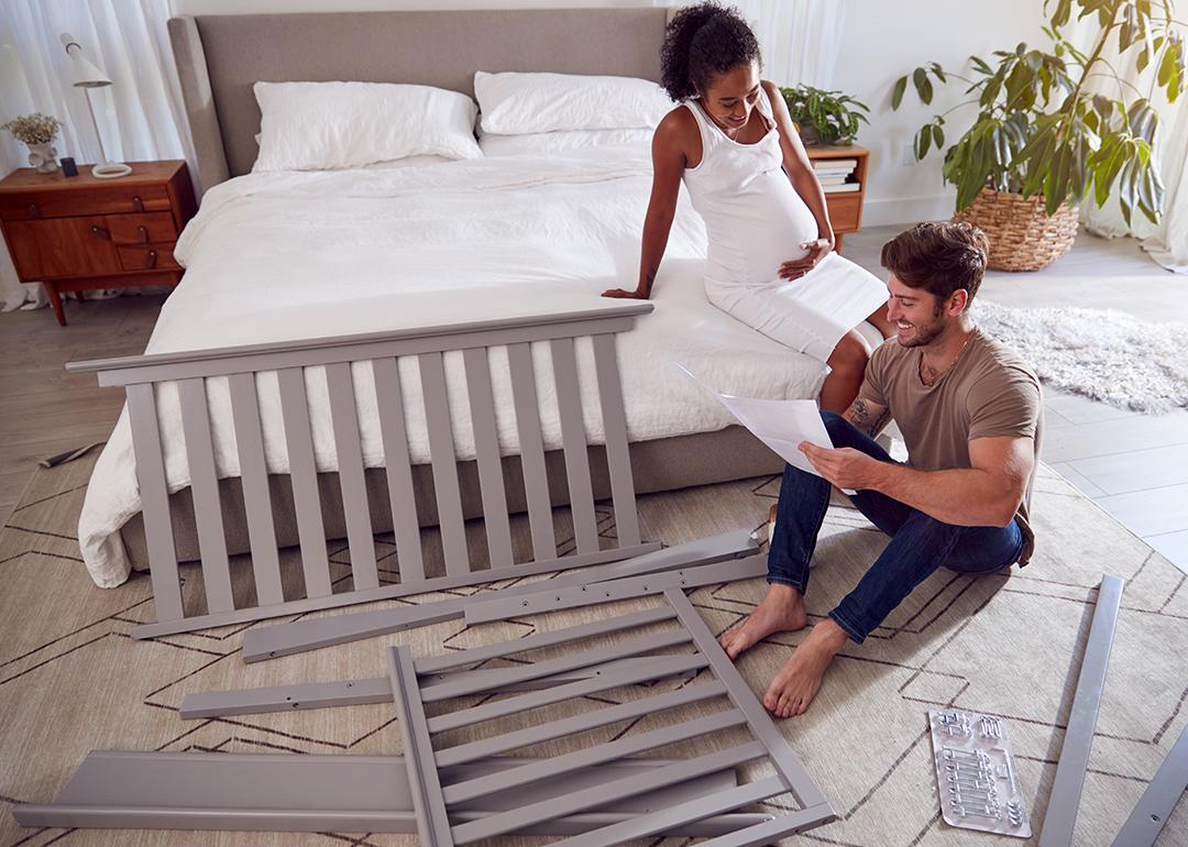 An expecting couple reading instructions on how to set up a cot.