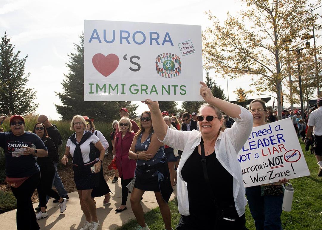 People in Denver protesting the federal government's stance on immigration; one holds a white posterboard that reads "Aurora loves immigrants"