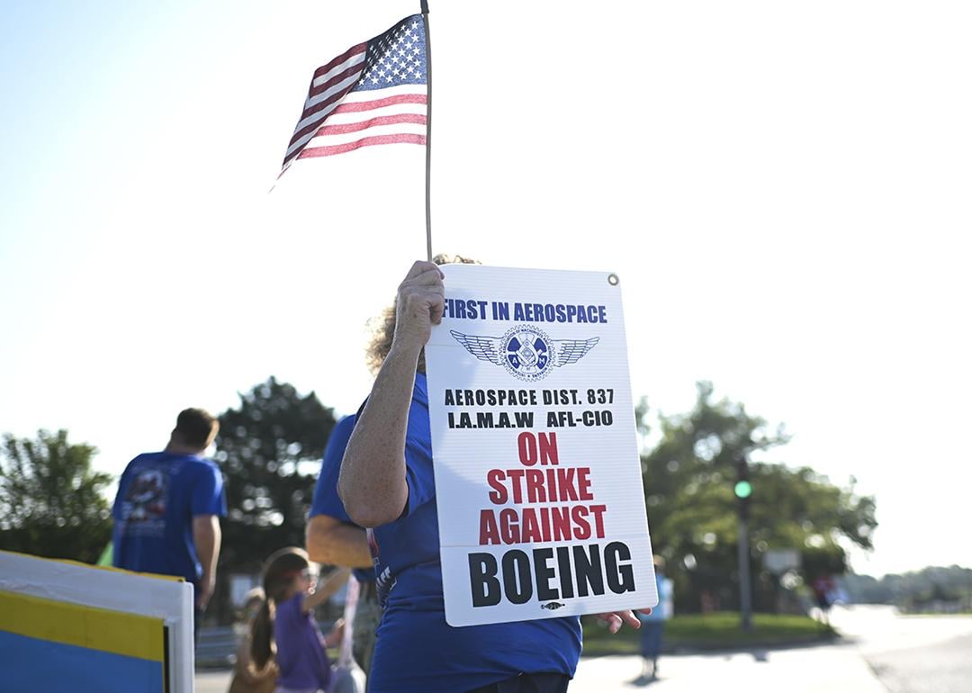 Boeing defense plant workers holding up "Strike Against Boeing" signs outside of a Boeing facility in Berkeley, Missouri.