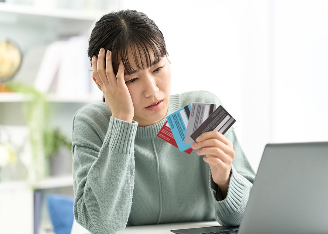 A woman looking worried at her four credit cards.