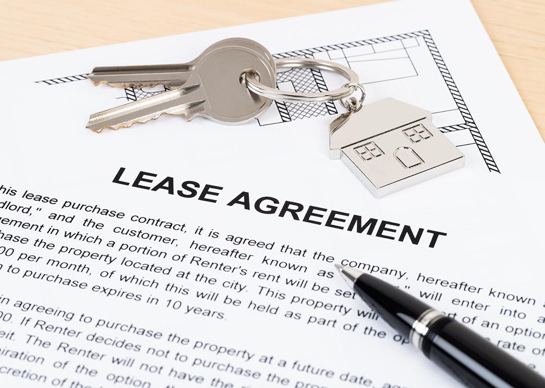 A mock up of a lease agreement document with house keys on top of it.