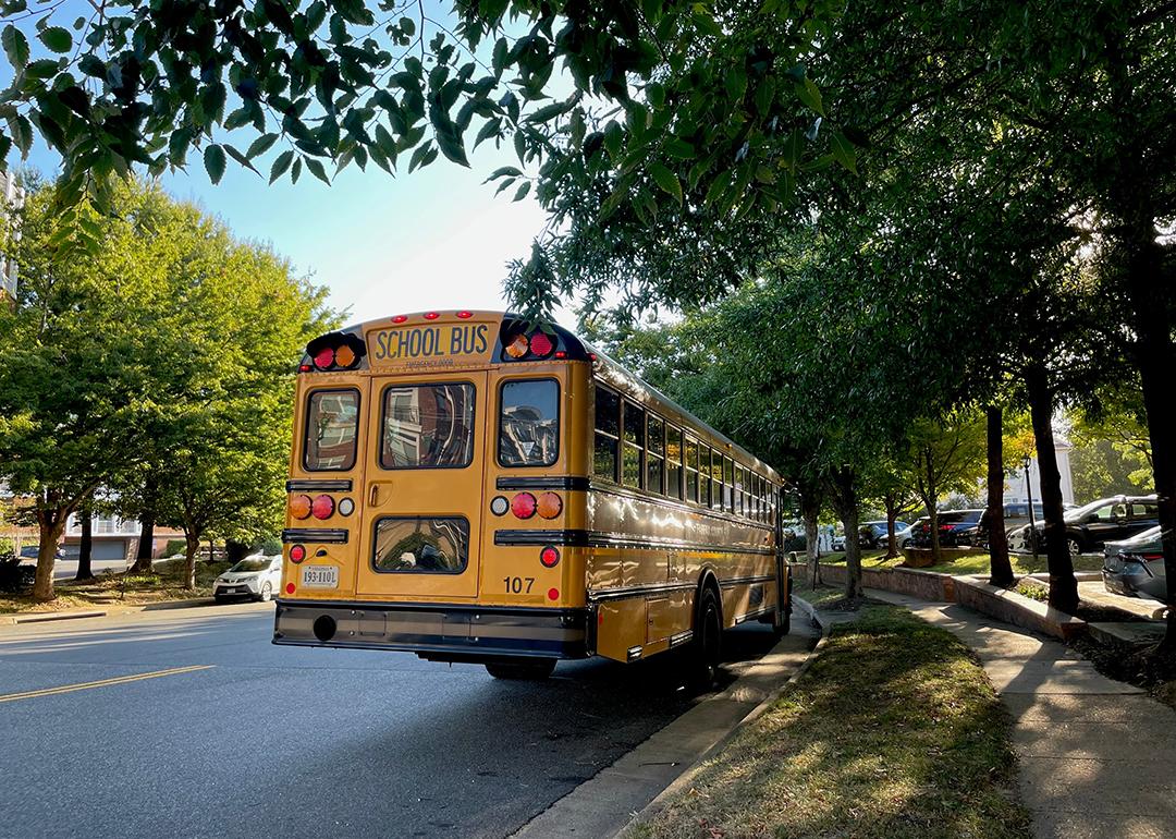 A yellow school bus waits by a bus stop in a family neighborhood in Fairfax County, Virginia.