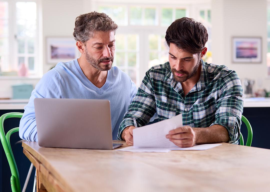 A gay couple at home checking finance documents.
