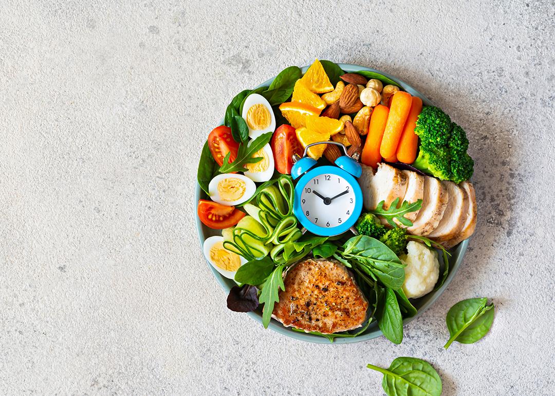 A bowl of vegetable meat with meat, fish, eggs, and a clock at the middle.
