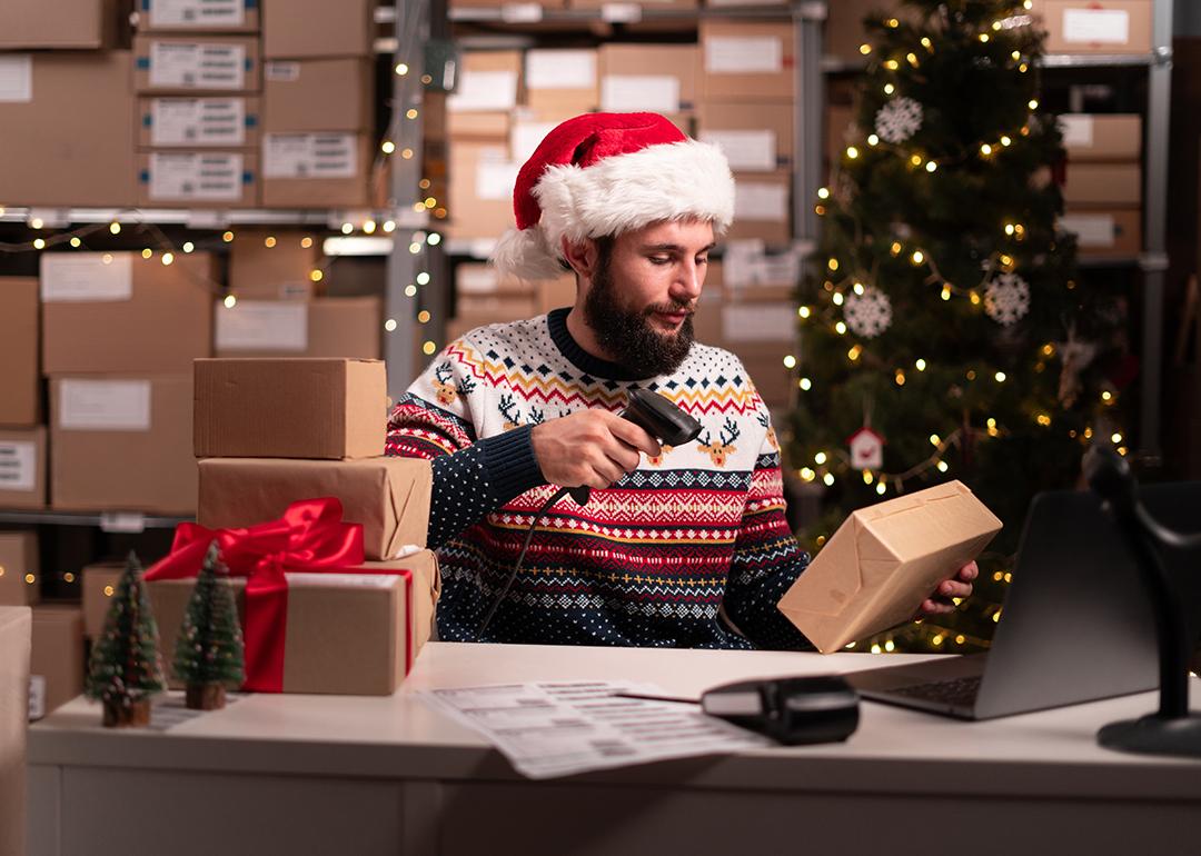 A warehouse worker in a Christmas outfit scanning barcodes on boxes during Christmas peak season.