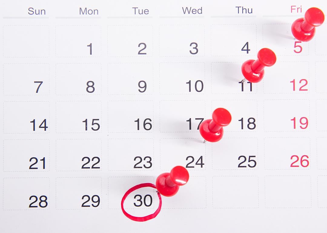 Pushpins on a calendar with an encircled date.