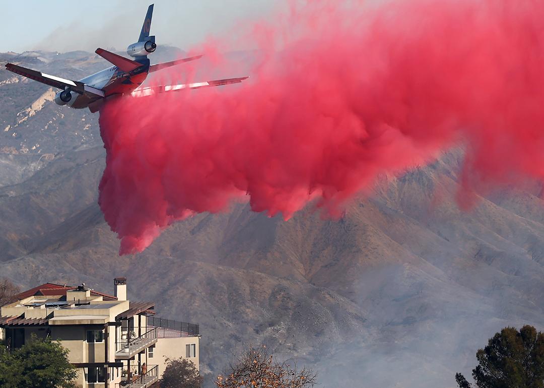 A firefighting aircraft drops the fire retardant Phos-Chek near homes during the Palisades Fire on January 10, 2025 in Topanga, California.