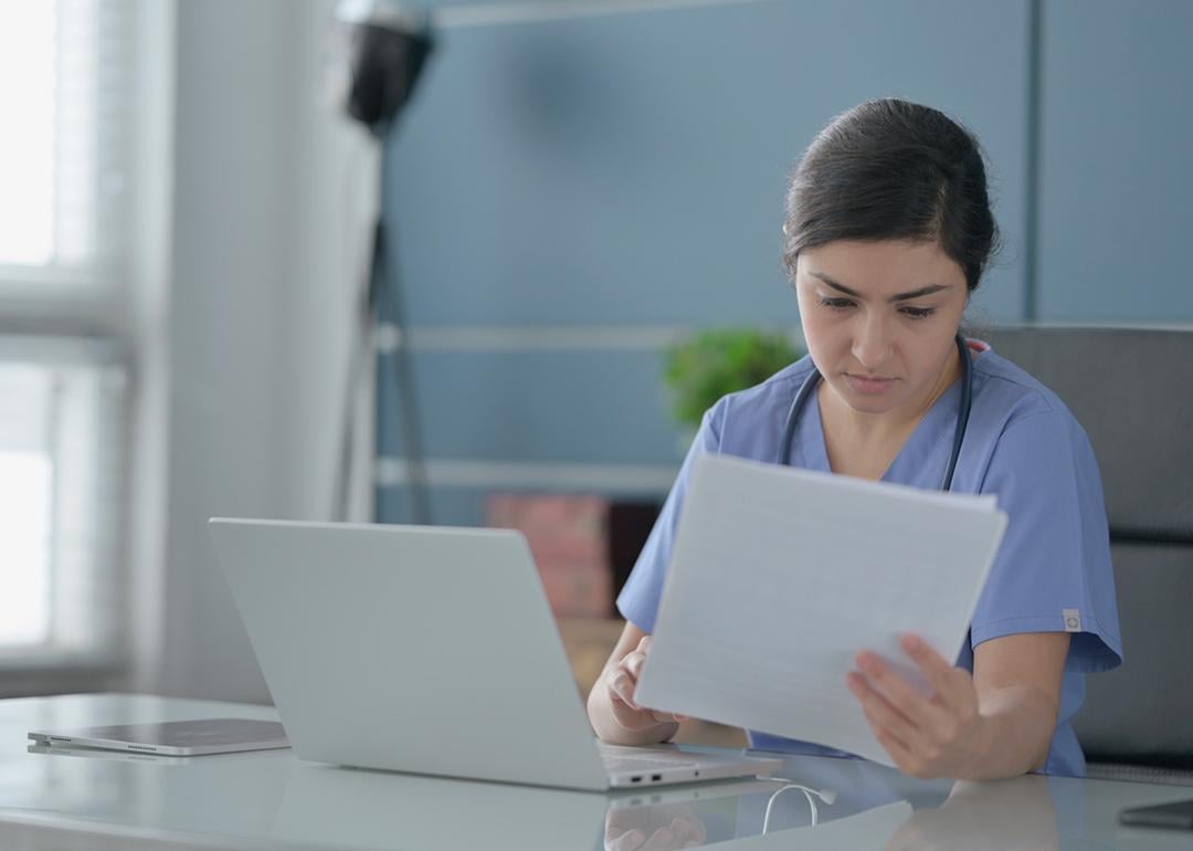 A female nurse reading documents in an office.
