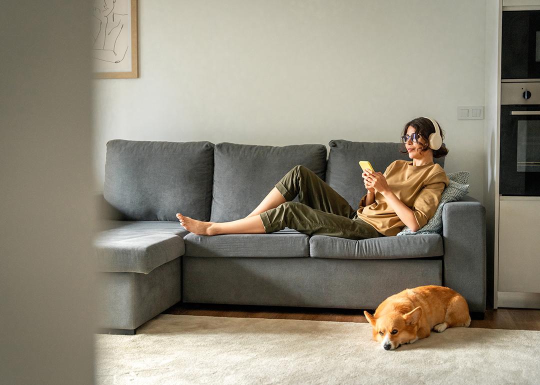 A young woman lying on couch while listening to music with her headphones.