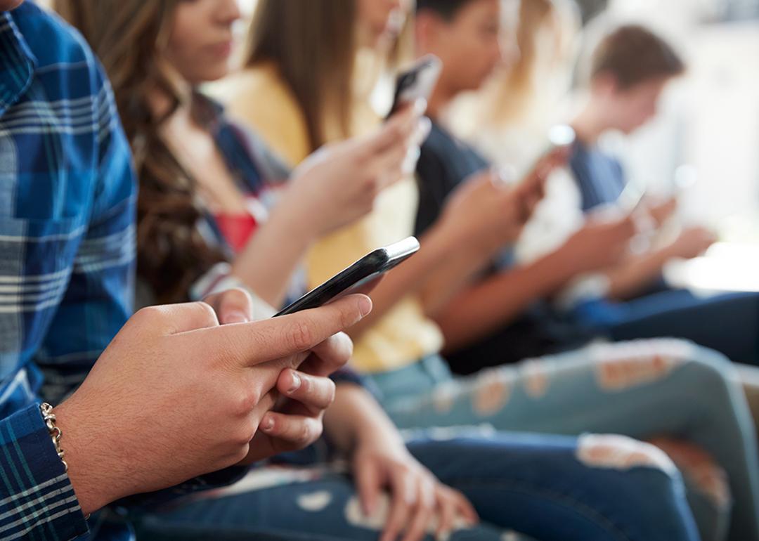 A row of high school students using mobile phones.