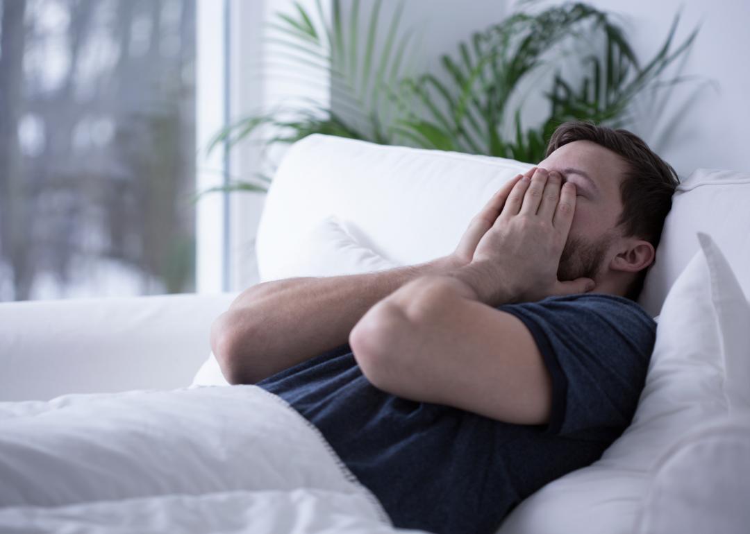 A man on bed struggling to sleep.