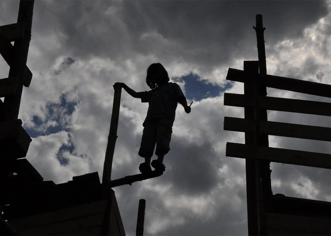 Silhouette of one of the children standing on the edge of an abandoned wooden fort.