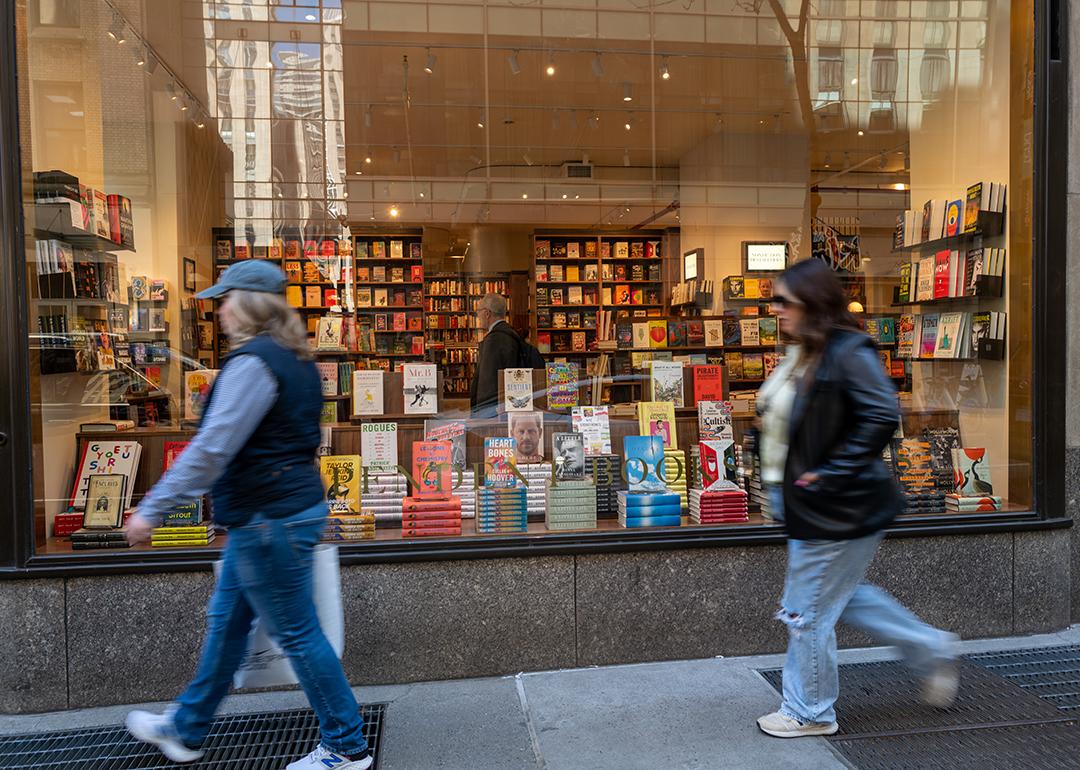 People passing by the glass display of a book store in Manhattan, New York.