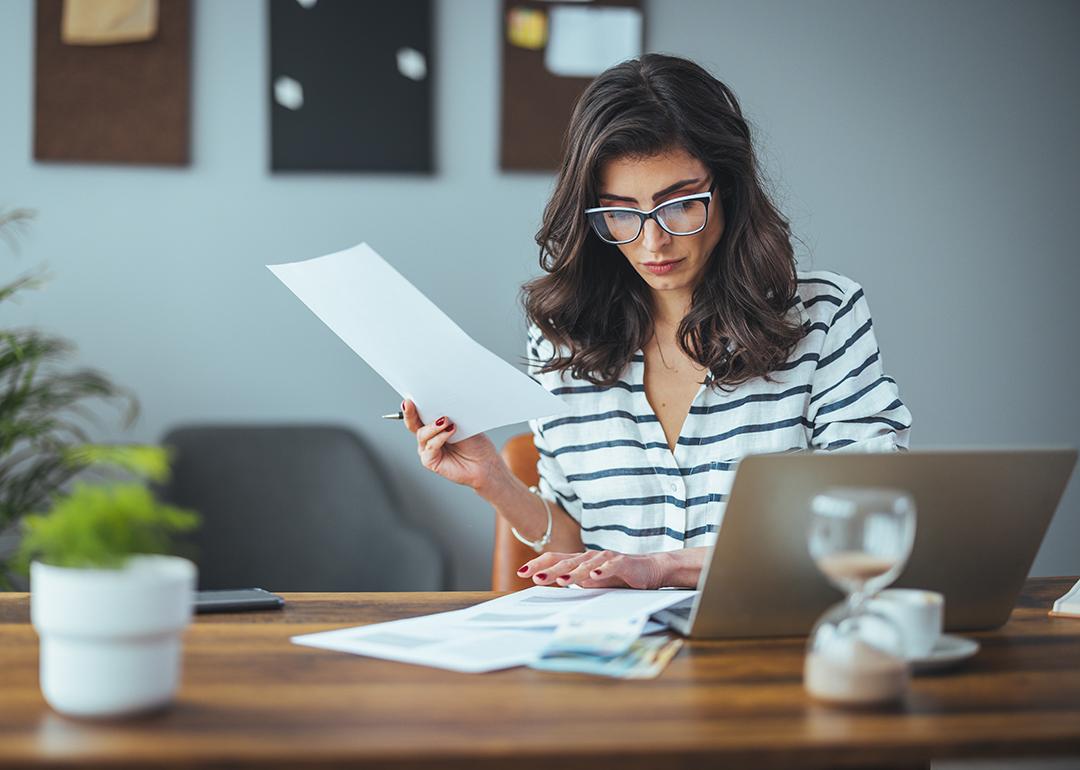 A businesswoman reading finance documents in an office.
