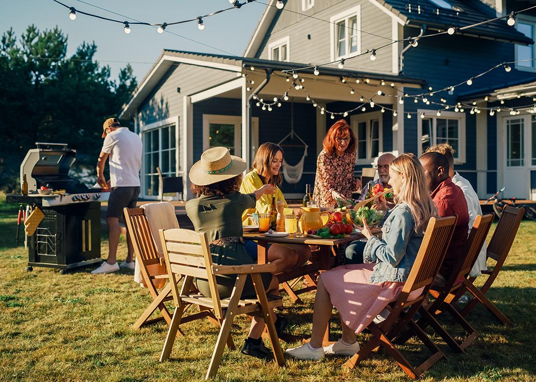 Family and friends dining outside a home during a barbecue dinner party.