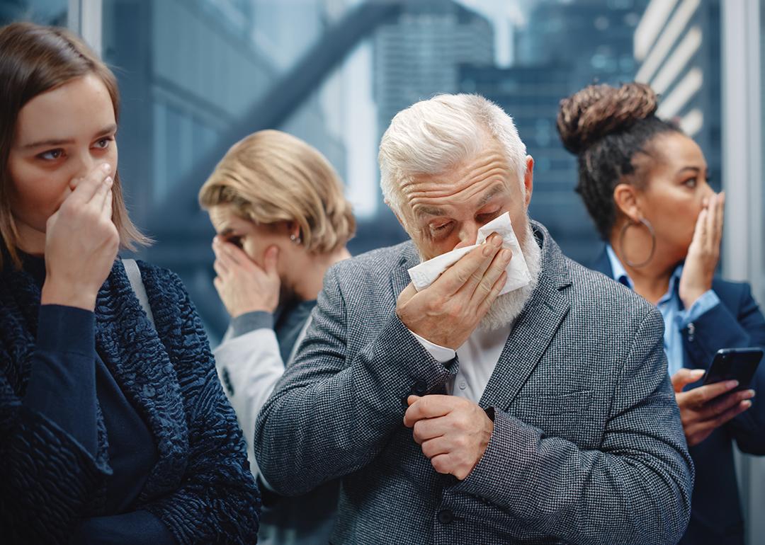 A middle-aged man sneezes in a crowded elevator.