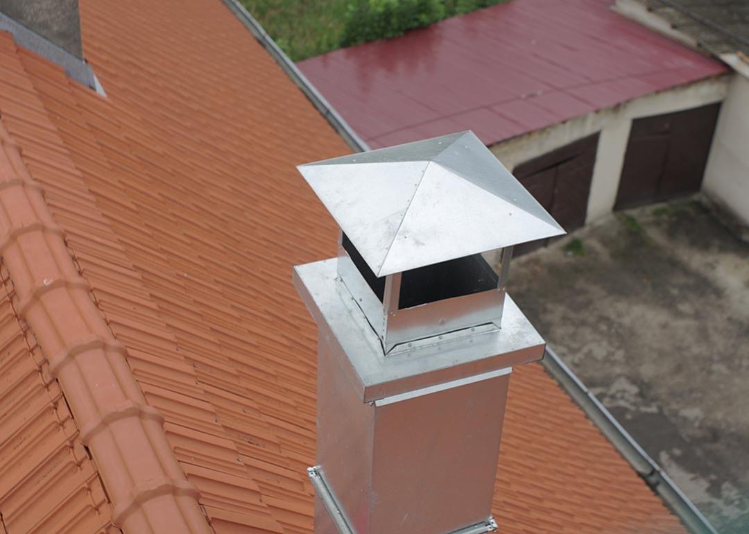 Aerial view of metal pipe chimney with cap on a Spanish tile roof.                          