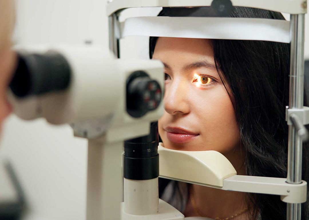A woman in front of a slit lamp as an eye specialist takes her vision test.